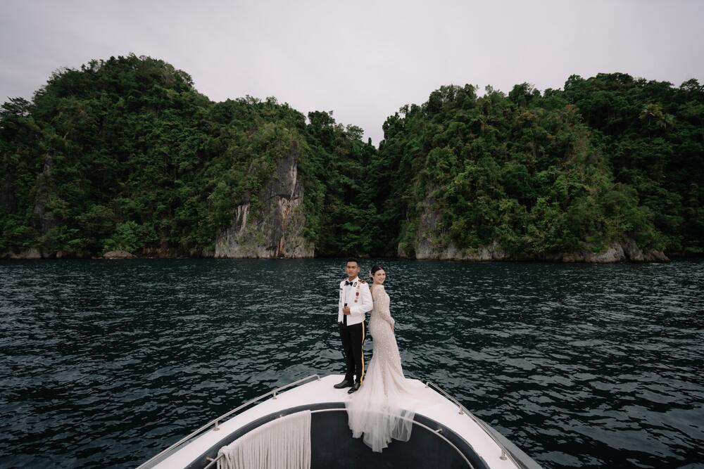 Pasangan pengantin dengan latar tebing karst dan perairan Papua